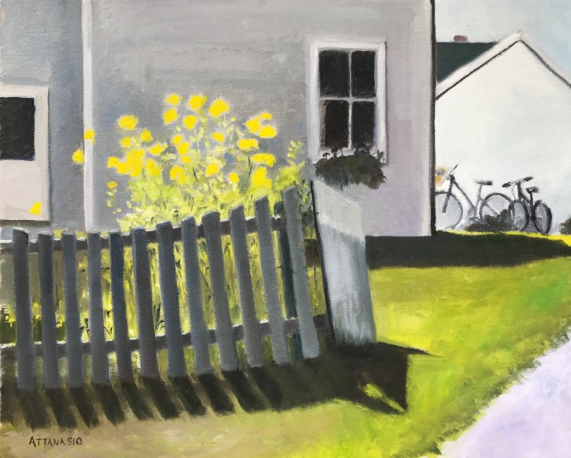 Yellow flowers and picket fence with house and bicycles in background
